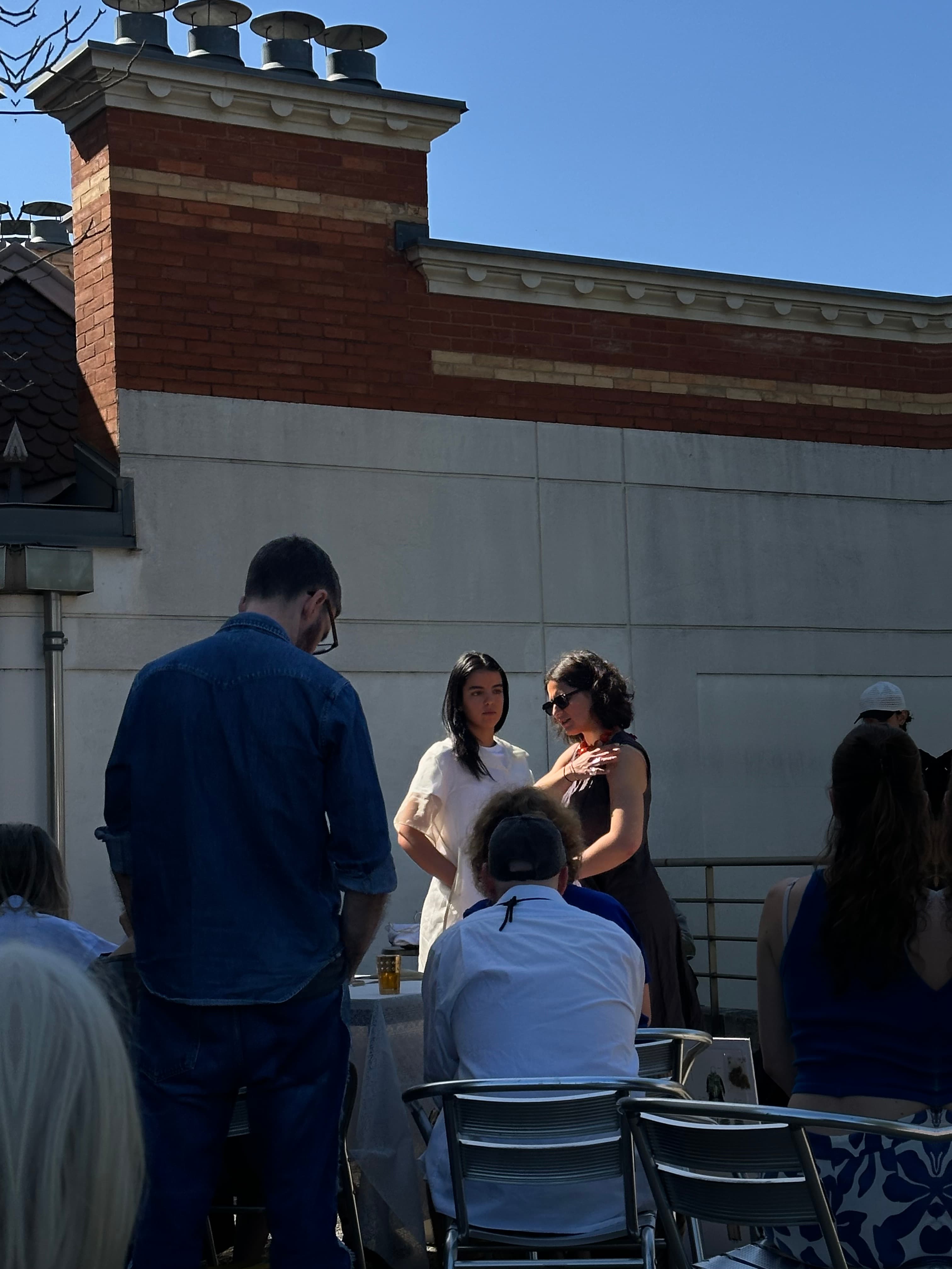 Presentation on a sunny rooftop, a model in a sheer white look standing before the seated jury