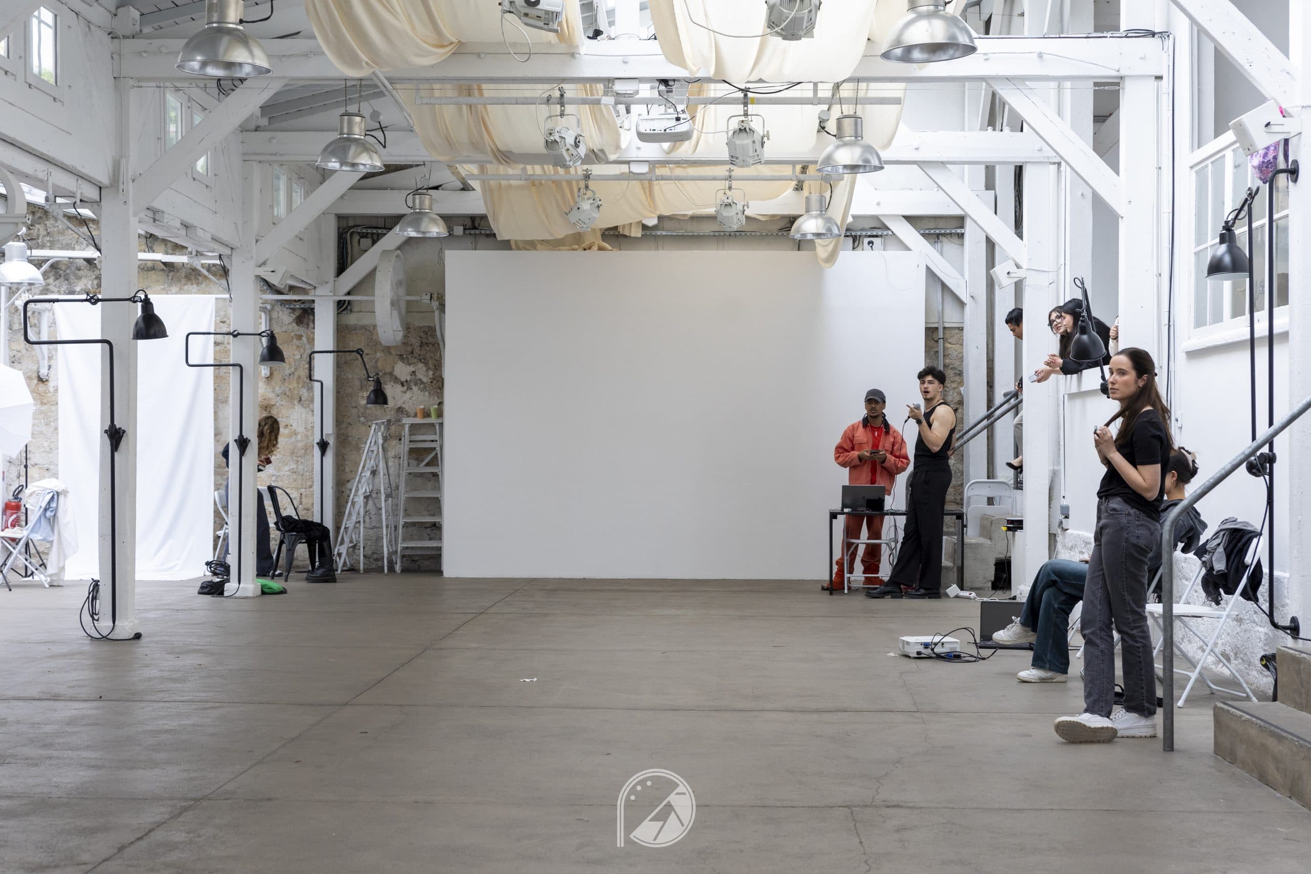 The industrial runway space of Le QG with a draped fabric ceiling and lighting rigs before the show