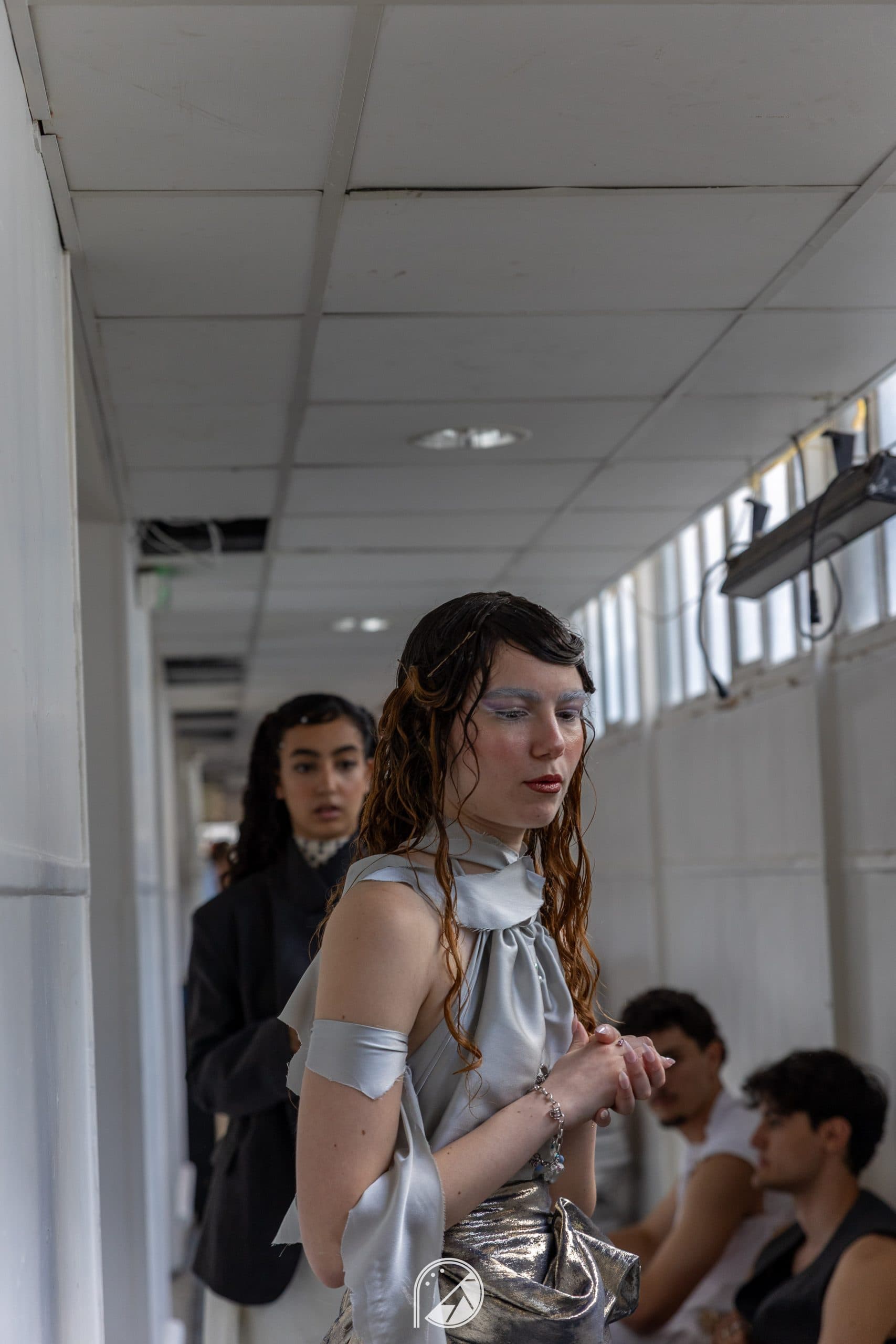 Model in the silver draped look waiting in the narrow backstage corridor