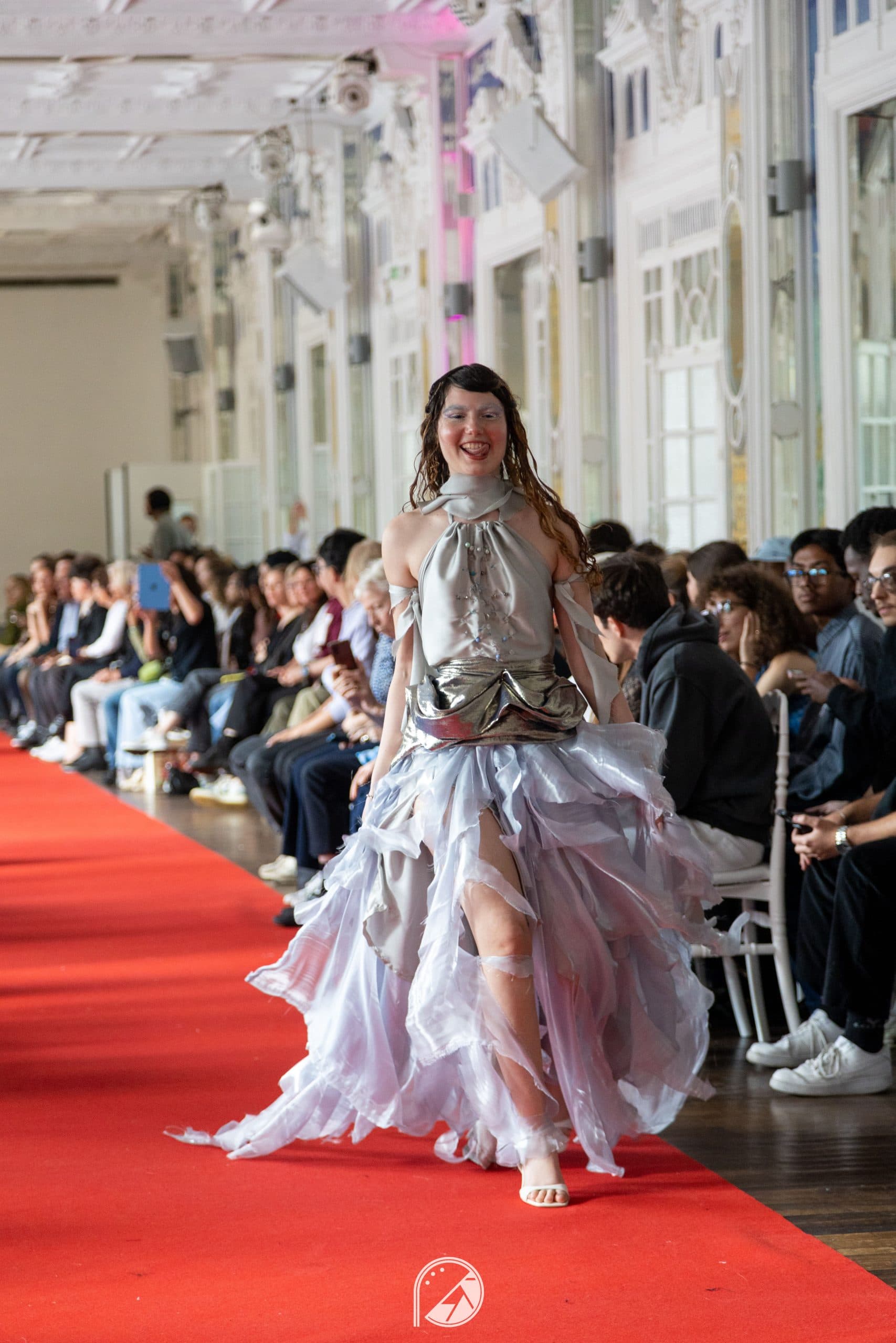 Model in a silver halter top, metallic draped waist and lilac organza ruffled skirt walking the red carpet of the Salon des Miroirs